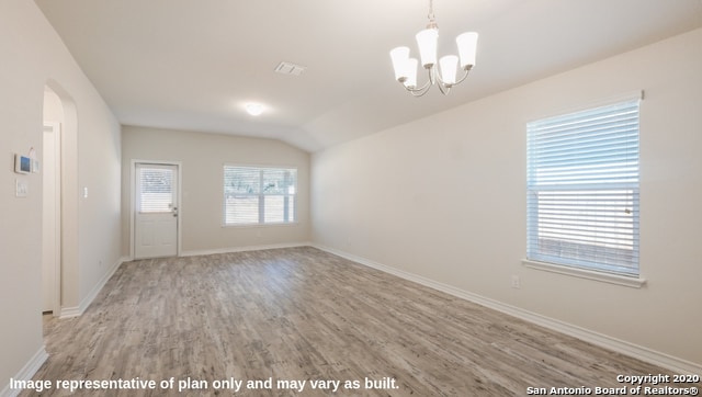 spare room featuring a notable chandelier, light hardwood / wood-style flooring, and vaulted ceiling