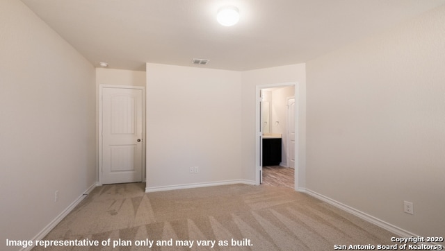 unfurnished bedroom with ensuite bath and light carpet