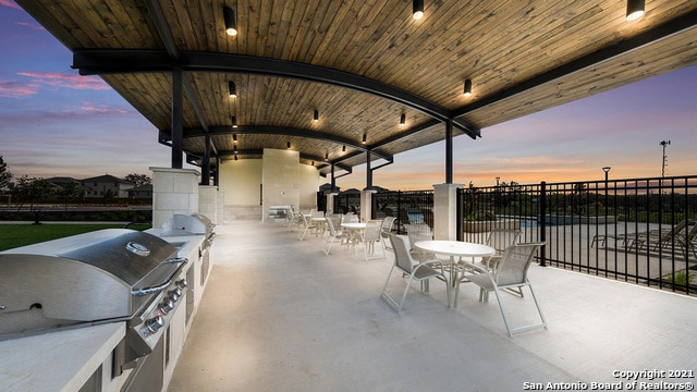 patio terrace at dusk featuring a grill