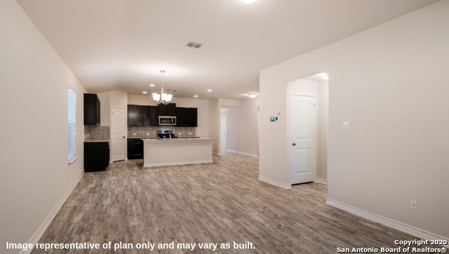 unfurnished living room with a chandelier and light hardwood / wood-style floors