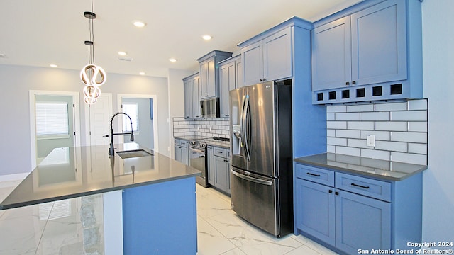 kitchen featuring tasteful backsplash, appliances with stainless steel finishes, a kitchen island with sink, pendant lighting, and sink