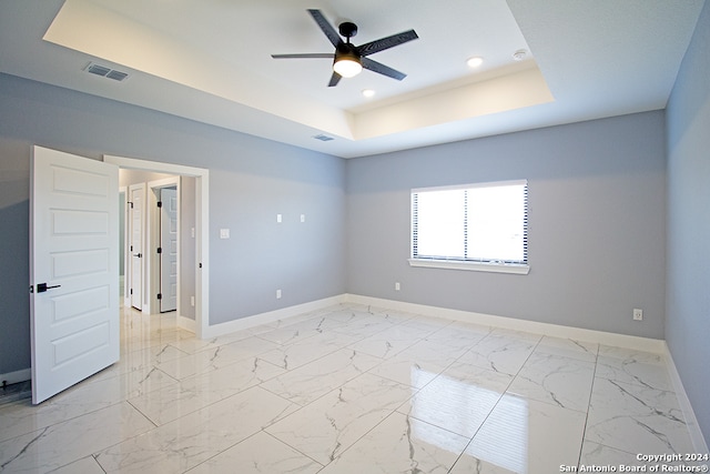 spare room with ceiling fan and a raised ceiling