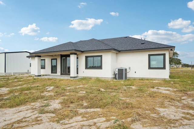 back of house with roof with shingles, stucco siding, central AC, and a patio area