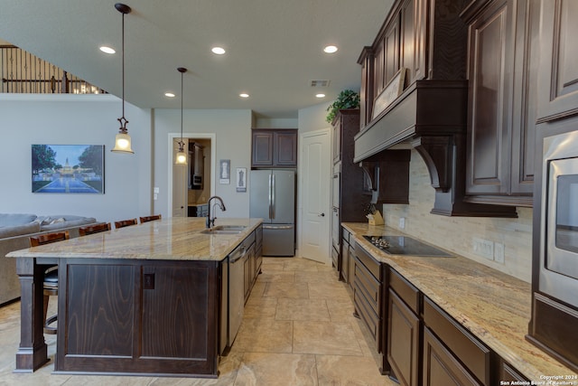 kitchen featuring appliances with stainless steel finishes, a center island with sink, dark brown cabinets, and sink