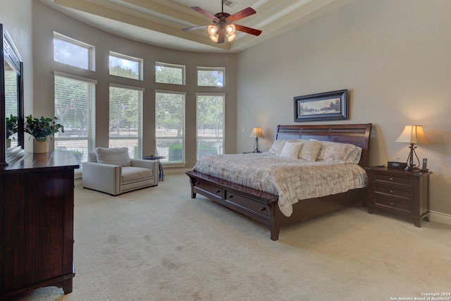 bedroom with ceiling fan, light carpet, and a high ceiling