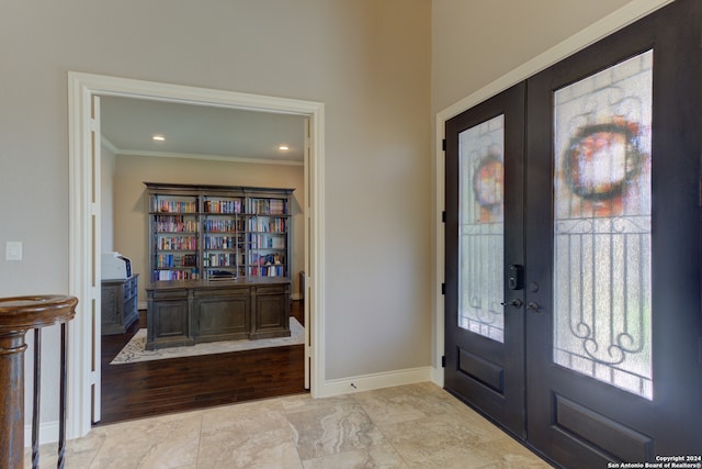 foyer entrance with ornamental molding, light wood-type flooring, and french doors