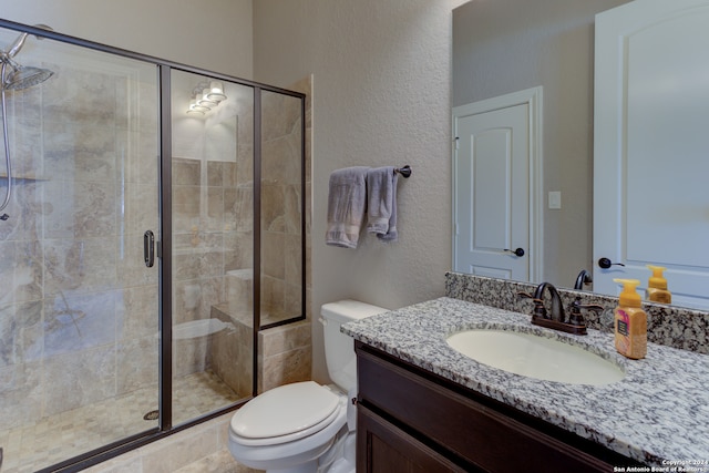 bathroom featuring vanity, a shower with shower door, and toilet