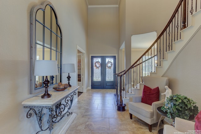 entrance foyer with a towering ceiling, french doors, and crown molding