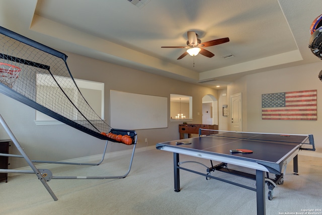 game room with light carpet, ceiling fan with notable chandelier, and a tray ceiling