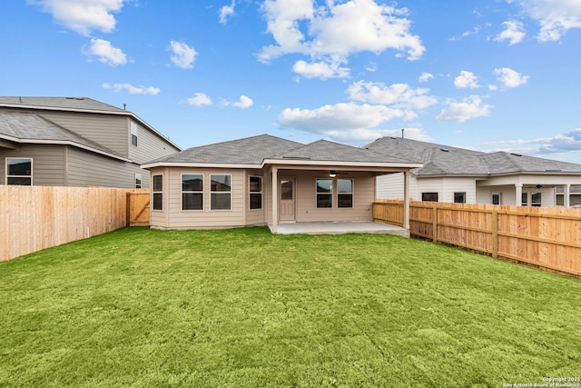 rear view of house with ceiling fan, a patio area, and a lawn