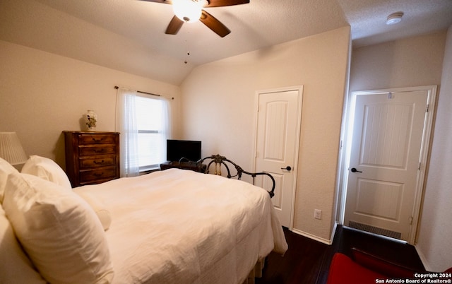 bedroom with ceiling fan, vaulted ceiling, and dark hardwood / wood-style flooring