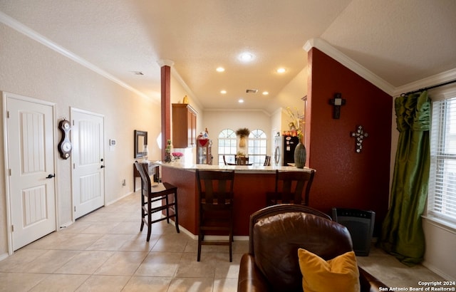 kitchen featuring light tile patterned flooring, stainless steel fridge, ornamental molding, kitchen peninsula, and a kitchen breakfast bar