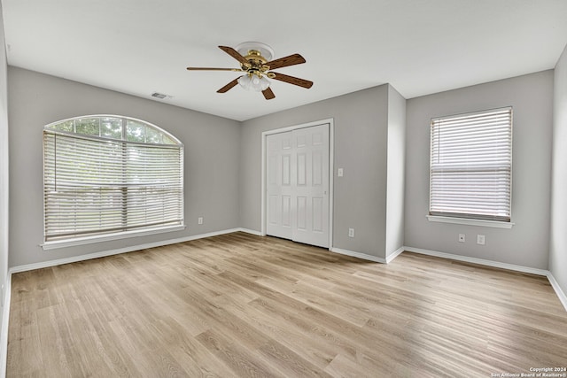 unfurnished bedroom with ceiling fan, a closet, and light hardwood / wood-style flooring