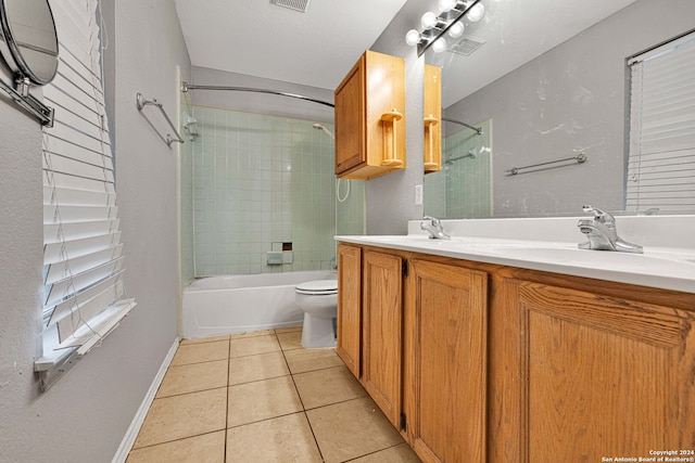 full bathroom with a textured ceiling, tiled shower / bath combo, tile patterned floors, vanity, and toilet