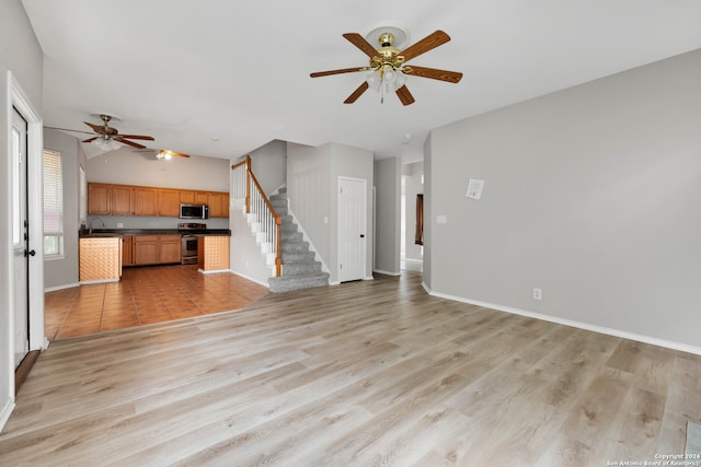 unfurnished living room with light hardwood / wood-style floors, ceiling fan, and sink