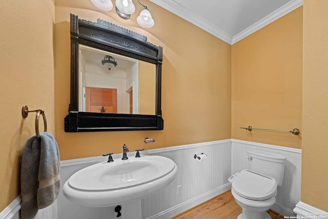 bathroom with wood-type flooring, ornamental molding, and toilet