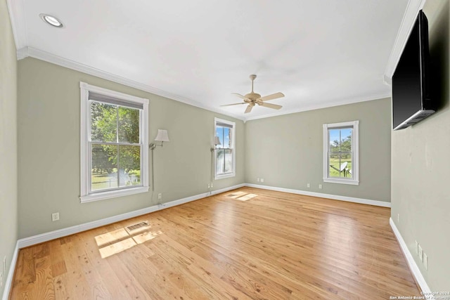 empty room featuring ornamental molding, a wealth of natural light, ceiling fan, and light wood-type flooring