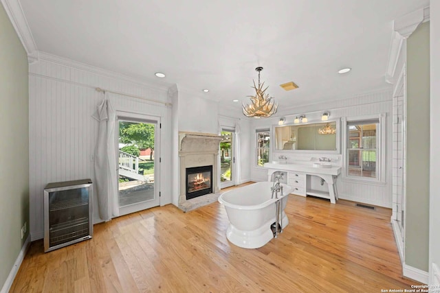 living room featuring light hardwood / wood-style flooring, an inviting chandelier, and crown molding