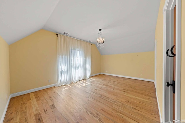 bonus room with light hardwood / wood-style floors, lofted ceiling, and an inviting chandelier