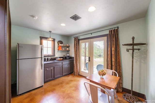 kitchen with pendant lighting, sink, plenty of natural light, and stainless steel refrigerator