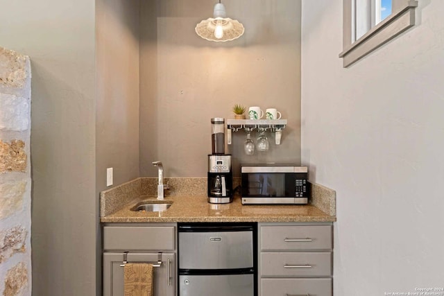 bar featuring stainless steel appliances, sink, and gray cabinetry