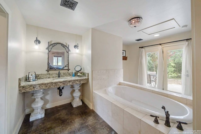 bathroom featuring tiled tub and sink