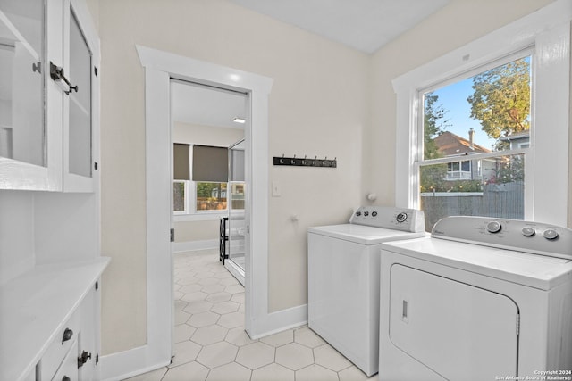 laundry area with light tile patterned floors, washing machine and clothes dryer, and cabinets