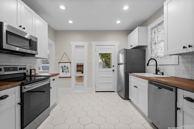 kitchen featuring sink, white cabinetry, decorative backsplash, appliances with stainless steel finishes, and wooden counters