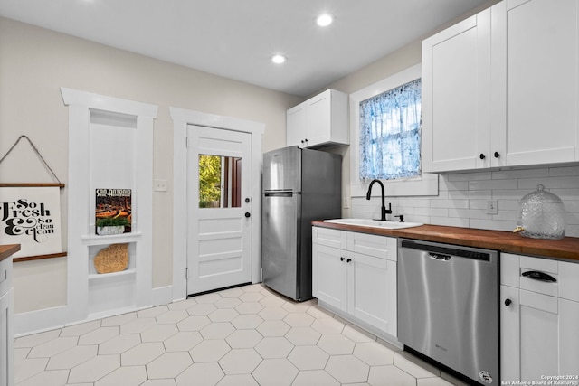 kitchen featuring stainless steel appliances, white cabinets, butcher block counters, and sink