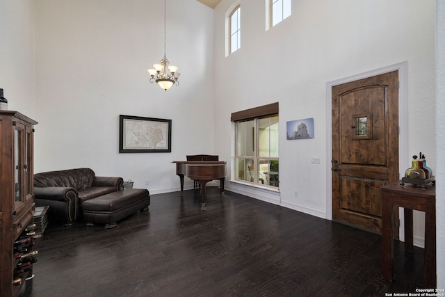 interior space with a notable chandelier, a towering ceiling, and dark wood-type flooring