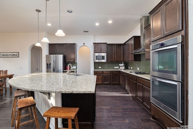 kitchen featuring tasteful backsplash, sink, an island with sink, appliances with stainless steel finishes, and dark hardwood / wood-style flooring