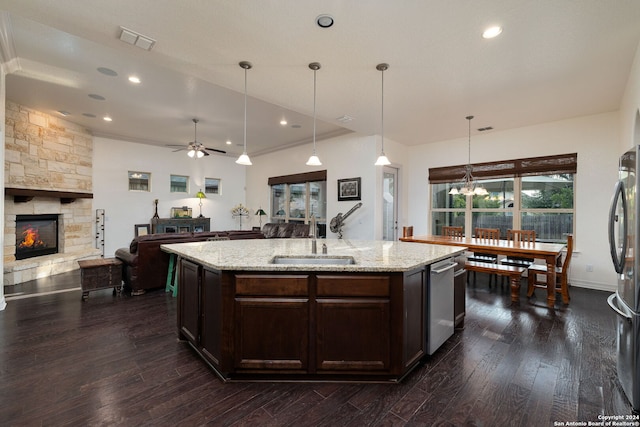 kitchen with hanging light fixtures, sink, a stone fireplace, ceiling fan with notable chandelier, and dark hardwood / wood-style flooring