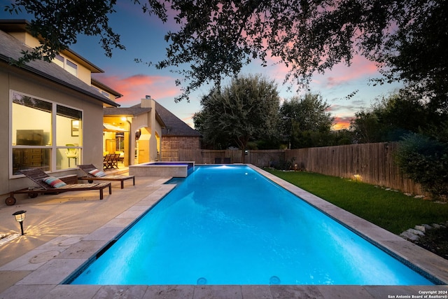 pool at dusk featuring an in ground hot tub and a patio area