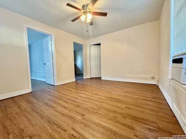 unfurnished room with ceiling fan, a textured ceiling, and light wood-type flooring