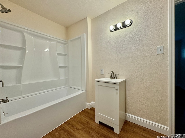 bathroom with a textured ceiling, vanity, hardwood / wood-style floors, and  shower combination