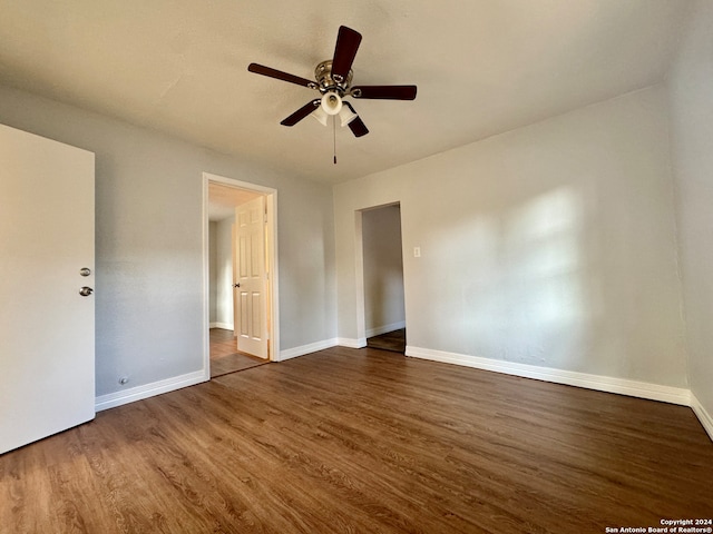 unfurnished bedroom with ceiling fan and dark wood-type flooring