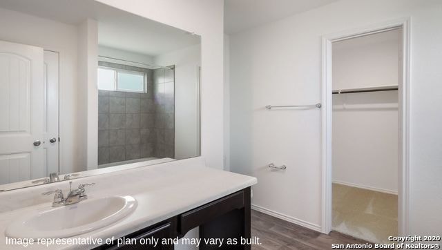 bathroom with a tile shower, hardwood / wood-style flooring, and vanity