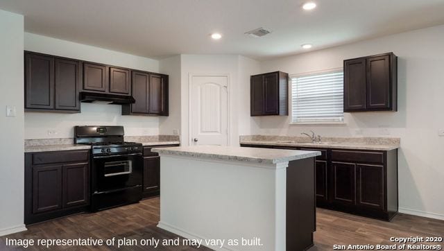 kitchen featuring dark brown cabinets, black gas range oven, a kitchen island, and dark hardwood / wood-style flooring