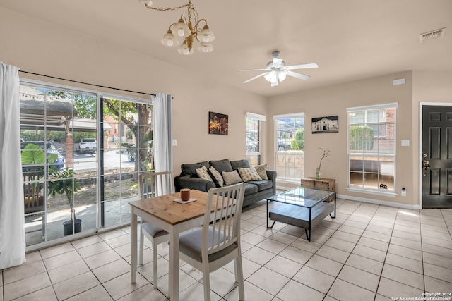 tiled living room with ceiling fan with notable chandelier