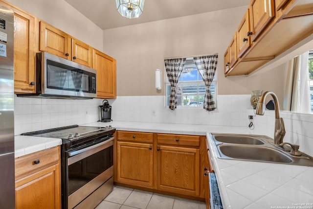 kitchen featuring stainless steel appliances, a wealth of natural light, tile counters, and sink