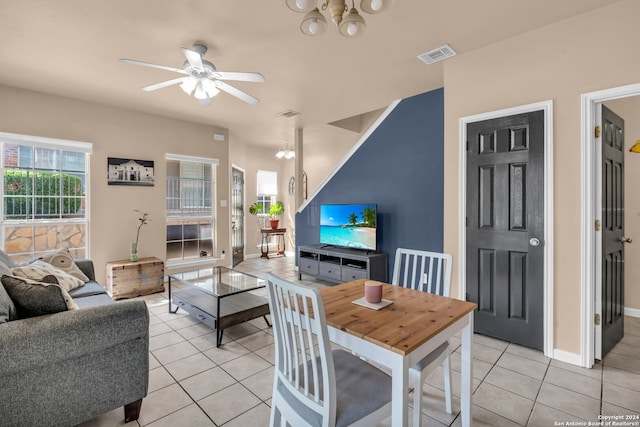 tiled dining room featuring ceiling fan with notable chandelier