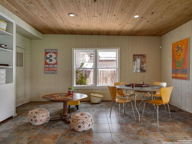 dining area with wooden ceiling, tile patterned flooring, and wood walls