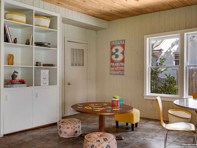 dining space featuring wood ceiling and wood walls