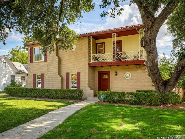 mediterranean / spanish-style home with a balcony and a front lawn