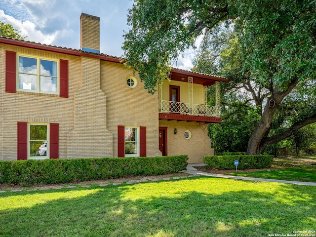 view of front facade featuring a balcony and a front yard