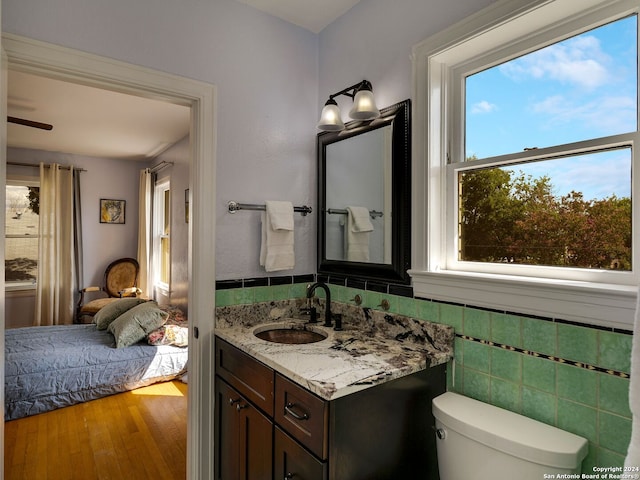 bathroom with a wealth of natural light, hardwood / wood-style floors, vanity, and toilet