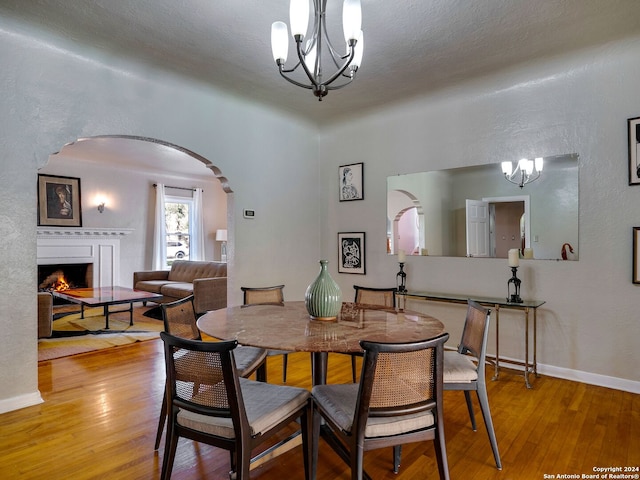 dining room with a textured ceiling, hardwood / wood-style floors, and a notable chandelier