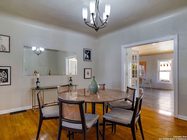 dining area featuring an inviting chandelier, wood-type flooring, and a textured ceiling