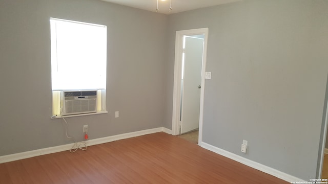 unfurnished room featuring cooling unit and light hardwood / wood-style flooring