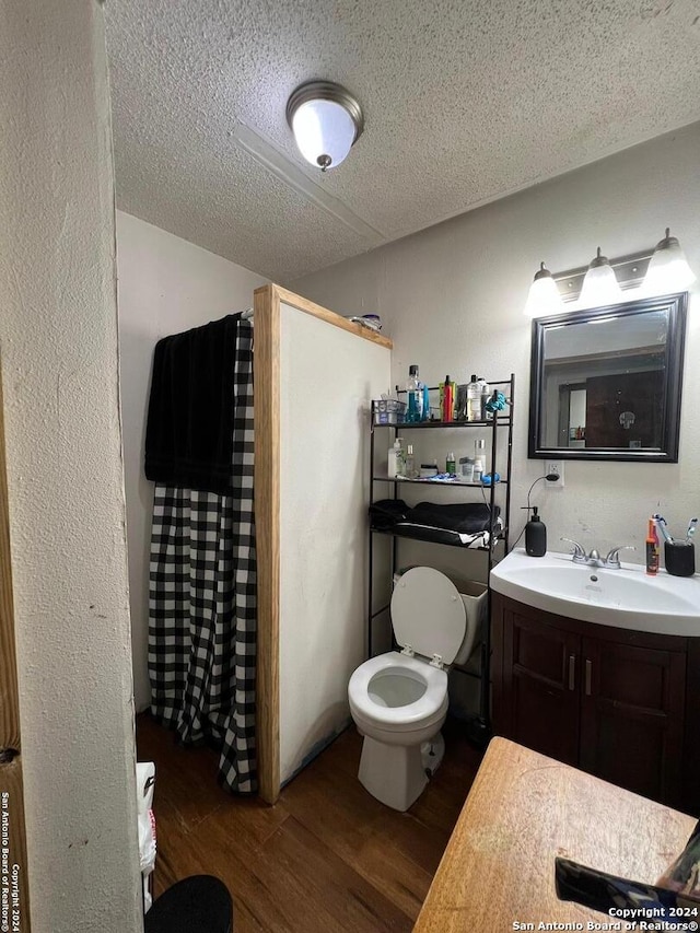 bathroom featuring vanity, a textured ceiling, a shower with shower curtain, hardwood / wood-style flooring, and toilet